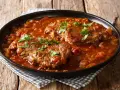 Due fette di carne alla pizzaiola, cotte lentamente in un sugo ricco di pomodoro e cipolle, guarnite con prezzemolo fresco.