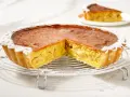 Una fetta di torta di mele con crema pasticcera, cosparsa di zucchero a velo, su una griglia.
