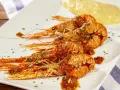 Scampi alla busara succulenti su piatto bianco, con un contorno di polenta gialla.