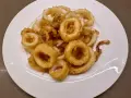 Un piatto bianco pieno di frittura di calamari dorata e croccante, un antipasto invitante.