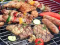 Grigliata di Ferragosto con spiedini, salsicce, bistecche, verdure e pomodori che cuociono sulla brace.