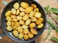 Patate novelle dorate e profumate in padella, condite con erbe aromatiche fresche, pronte per essere gustate.