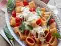 Piatto di pasta con pomodorini e abbondante stracciatella cremosa, guarnito con basilico fresco.