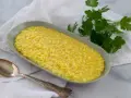 Un cremoso risotto allo zafferano in un piatto ovale, con un cucchiaio d'argento e un rametto di prezzemolo fresco.