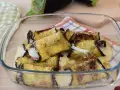 Involtini di melanzane alla siciliana appena sfornati, filanti e dorati, in una pirofila di vetro.