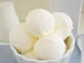 Coppa di gelato cremoso, risultato di una perfetta ricetta gelato con gelatiera. Latte fresco e cucchiaino bianco.