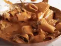 Un primo piatto cremoso e invitante: paccheri alla Vittorio, conditi con una ricca salsa arancione e guarniti con parmigiano.