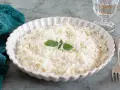 Piatto di riso in cagnone, cremoso e invitante, guarnito con foglie di salvia e parmigiano grattugiato.