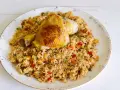 Fusi di pollo in padella serviti su un letto di riso saltato con verdure colorate.