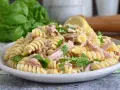 Un piatto di pasta fredda tonno, con fusilli, tonno sfilacciato, prezzemolo fresco e scorza di limone. Perfetta per un pranzo estivo.