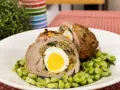 Fettina di carne ripiena con uovo sodo e spinaci, servita su un letto di fave.