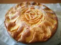 Deliziosa torta di mele senza glutine, con mele disposte a rosa al centro e spolverata di zucchero a velo.