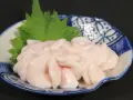 Piatto di lattume di tonno, delicato e rosato, guarnito con una foglia verde su un piatto decorato.
