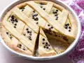 Una deliziosa crostata di ricotta con gocce di cioccolato, con una fetta tagliata per mostrare il ripieno cremoso.