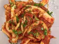 Un piatto invitante di calamari in umido, conditi con una ricca salsa al pomodoro e prezzemolo fresco tritato.