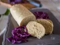 Un gustoso salame di tonno, affettato e servito con cavolo rosso tritato su un piatto grigio.
