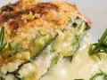 Una fetta di parmigiana di zucchine bianca senza besciamella, dorata e croccante, con rosmarino fresco.