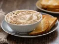 Una ciotola di cremosa mousse di tonno, servita con fette di pane tostato dorato. Perfetta per un aperitivo veloce.