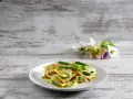Lasagne al pesto con fagiolini e patate, un piatto colorato e gustoso su un tavolo di legno.