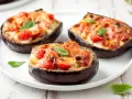 Melanzane ripiene al forno velocissime, con pomodorini, formaggio filante e basilico fresco. Un piatto invitante e facile da preparare.
