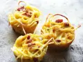 Tre deliziose frittate di pasta, dorate e con pezzetti di pancetta, pronte per essere gustate.