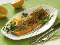 Deliziosa trota salmonata al forno, croccante e profumata, servita con limone fresco e erbe aromatiche.