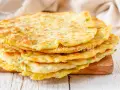 Una pila di schiacciate di zucchine dorate e soffici, cosparse di parmigiano, pronte per essere gustate.
