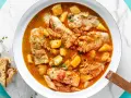Un saporito merluzzo in umido con patate e pomodoro, guarnito con prezzemolo fresco e accompagnato da pane tostato.