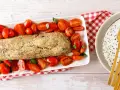 Polpettone di melanzane dorato e croccante, circondato da pomodorini freschi e basilico, pronto per essere gustato.