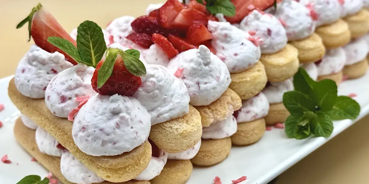 Delizioso tiramisù alle fragole, un dolce a strati con savoiardi, crema rosa e fragole fresche, guarnito con menta.