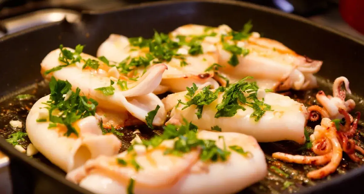 Seppie alla griglia succulente, cosparse di prezzemolo fresco, cuociono in una padella scanalata, pronte per essere gustate.