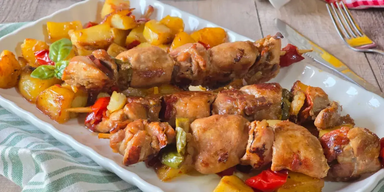 Spiedini di carne succulenti con patate arrosto e peperoni colorati, un piatto invitante e saporito.