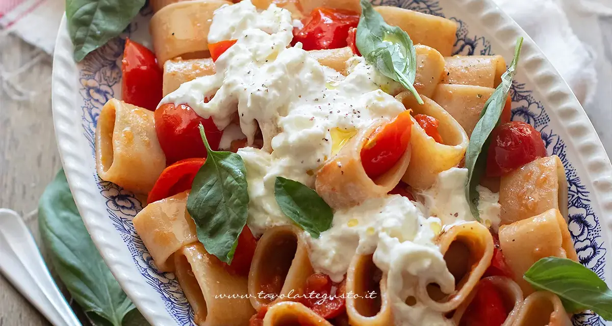 Piatto di pasta con pomodorini e abbondante stracciatella cremosa, guarnito con basilico fresco.