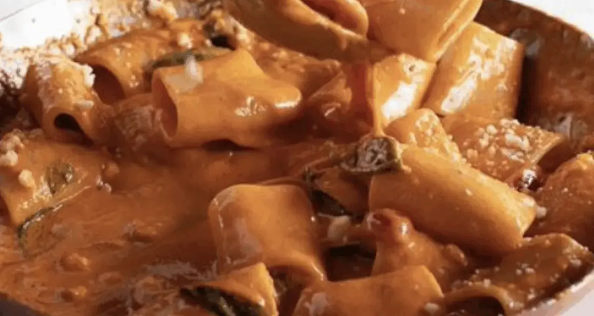Un primo piatto cremoso e invitante: paccheri alla Vittorio, conditi con una ricca salsa arancione e guarniti con parmigiano.