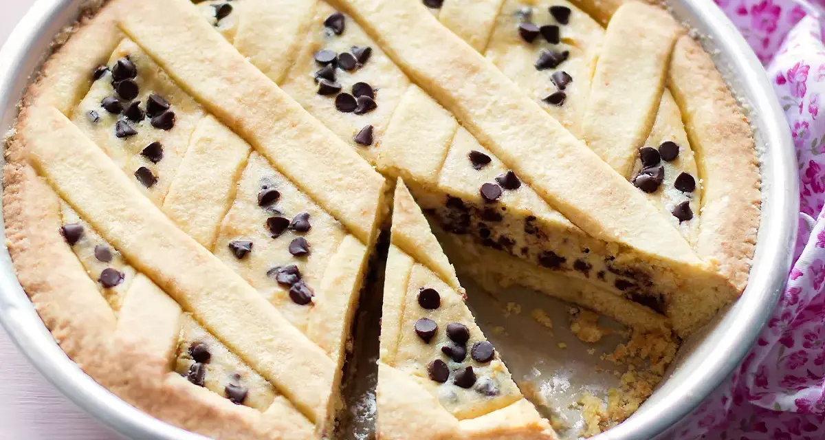 Una deliziosa crostata di ricotta con gocce di cioccolato, con una fetta tagliata per mostrare il ripieno cremoso.