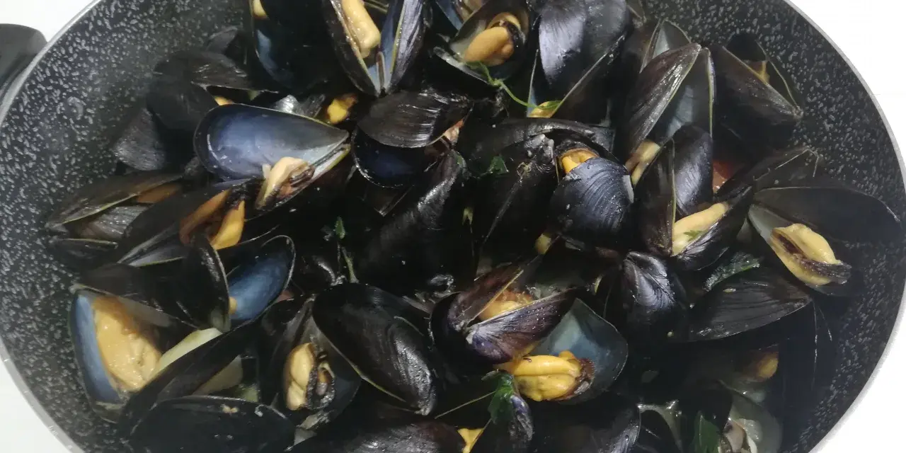 Un saporito sautè di cozze appena cucinato, con gusci aperti che rivelano la polpa succulenta.
