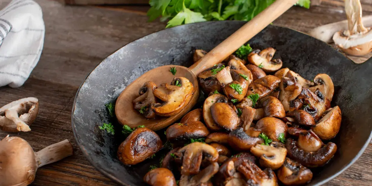 Funghi in padella dorati e saporiti, guarniti con prezzemolo fresco, pronti per essere gustati.