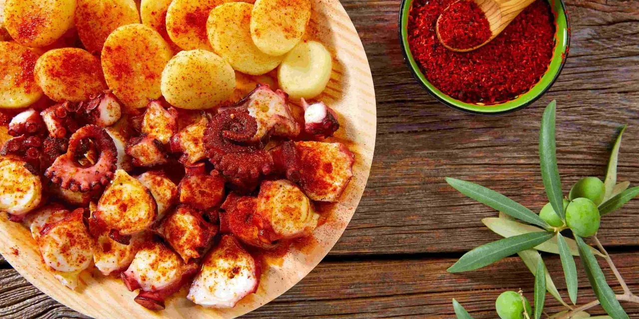 Piatto di polpo alla gallega con patate, paprika e rametto di ulivo.