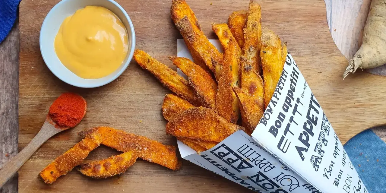 Patate dolci al forno croccanti, servite in un cono di carta con una salsa cremosa e paprika.