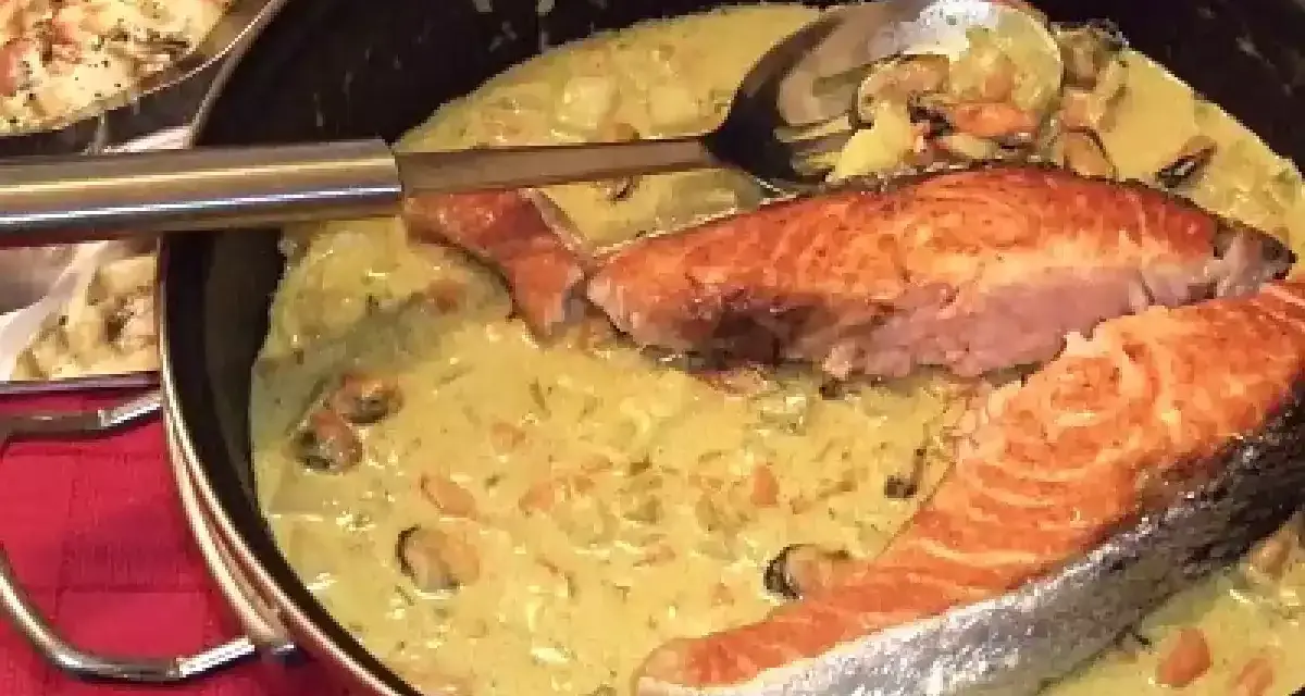Delizioso trancio di salmone in padella con una cremosa salsa gialla e cozze.