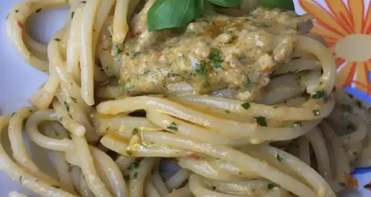Un piatto invitante di pasta alla carlofortina, condita con un sugo cremoso e guarnita con basilico fresco.