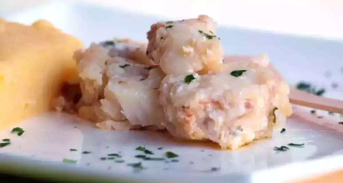 Piatto di baccalà alla vicentina cremoso e saporito, servito con una porzione di polenta morbida.