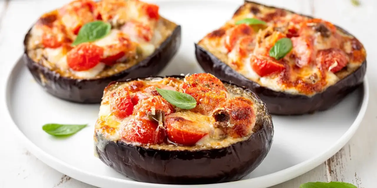 Melanzane ripiene al forno velocissime, con pomodorini, formaggio filante e basilico fresco. Un piatto invitante e facile da preparare.