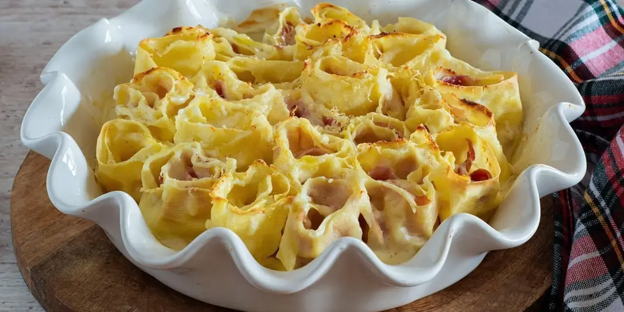 Deliziosi nidi di rondine ripieni di prosciutto e formaggio, cotti al forno in una teglia bianca.