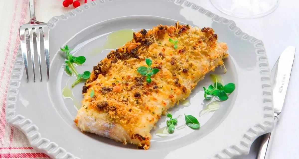Delizioso merluzzo impanato al forno, dorato e croccante, guarnito con erbe fresche e servito su un piatto grigio.