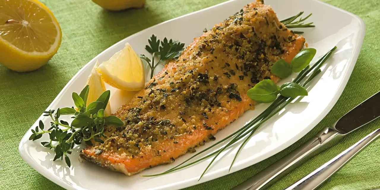 Deliziosa trota salmonata al forno, croccante e profumata, servita con limone fresco e erbe aromatiche.