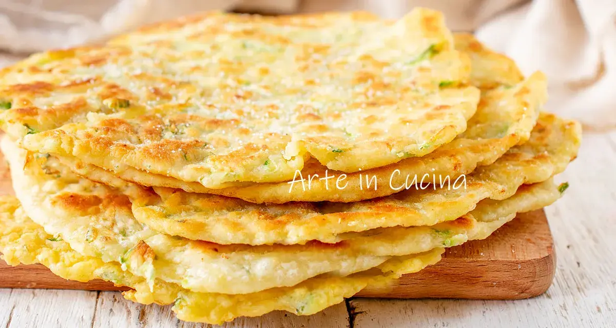 Una pila di schiacciate di zucchine dorate e soffici, cosparse di parmigiano, pronte per essere gustate.