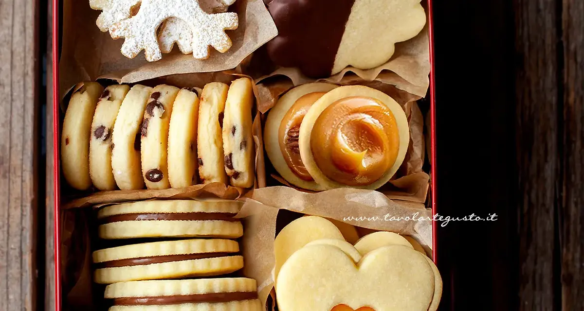Scatola piena di biscotti al burro: a fiocco di neve, al cioccolato, con ripieno di caramello e a forma di cuore.