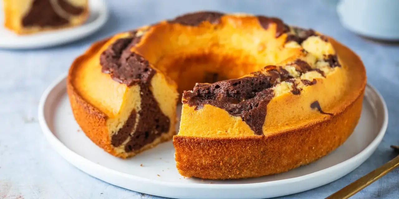 Un ciambellone soffice bicolore, con un invitante contrasto tra pasta chiara e cacao, pronto per essere gustato.