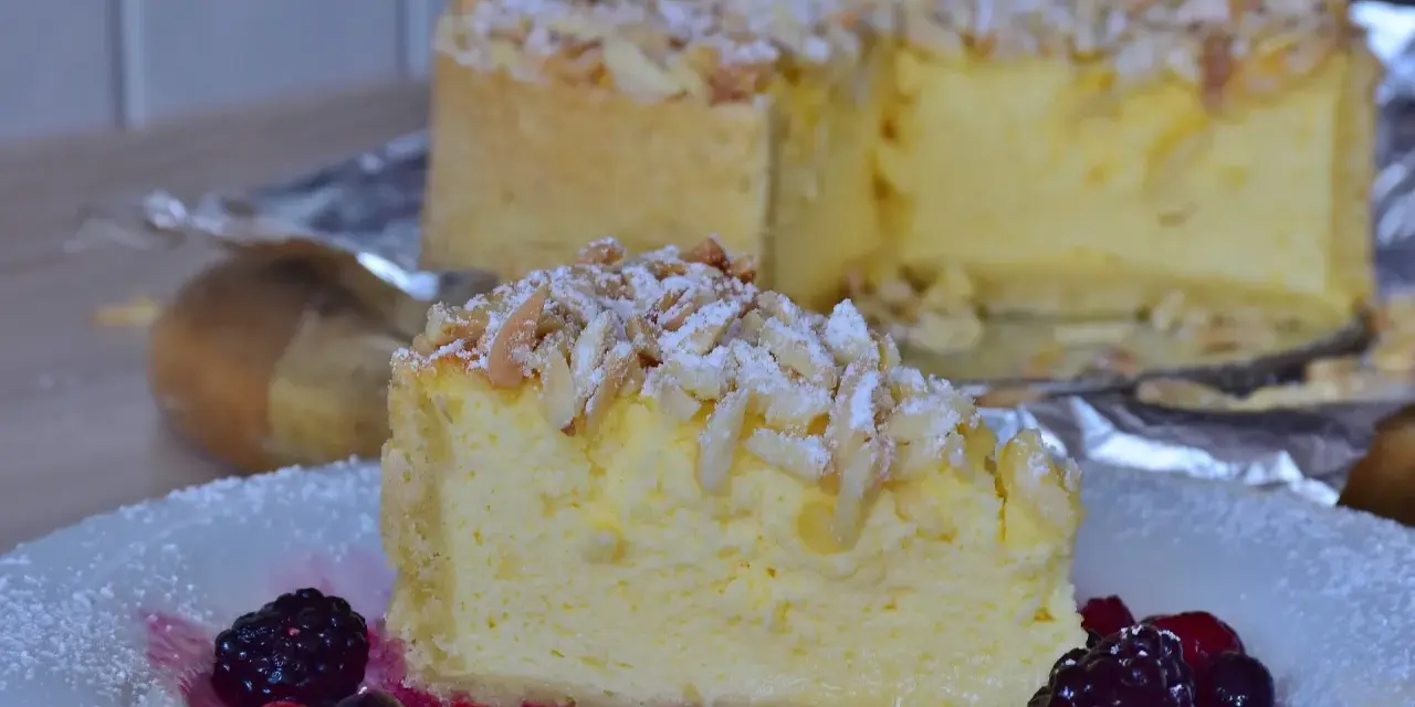 Una fetta di torta di riso cremosa, guarnita con mandorle a lamelle e frutti di bosco, su un piatto bianco.